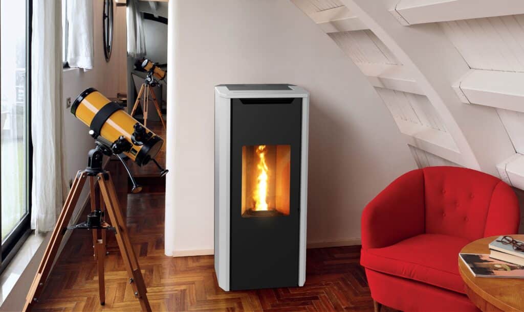 Intérieur chaleureux avec poêle à pellets noir et blanc, télescope jaune près de la fenêtre et fauteuil rouge confortable sous un plafond mansardé.