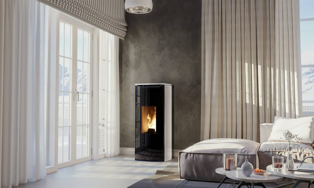 Salon moderne avec cheminée noire et baies vitrées sur montagnes enneigées. Lumière du soleil inonde canapé confortable et rideaux clairs.